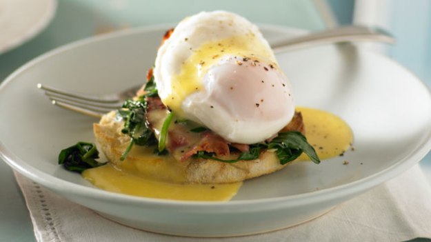 Eggs Benedict with spinach and bacon served on an English muffin