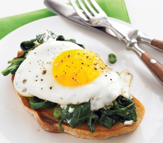 Home-made poached egg on a bed of garlic spinach served on GF toast